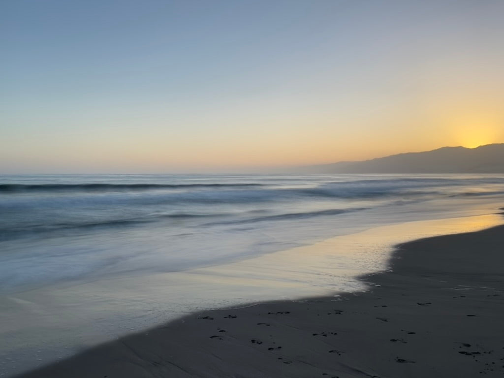 Golden dusk light over the shoreline and mountains by Samson California